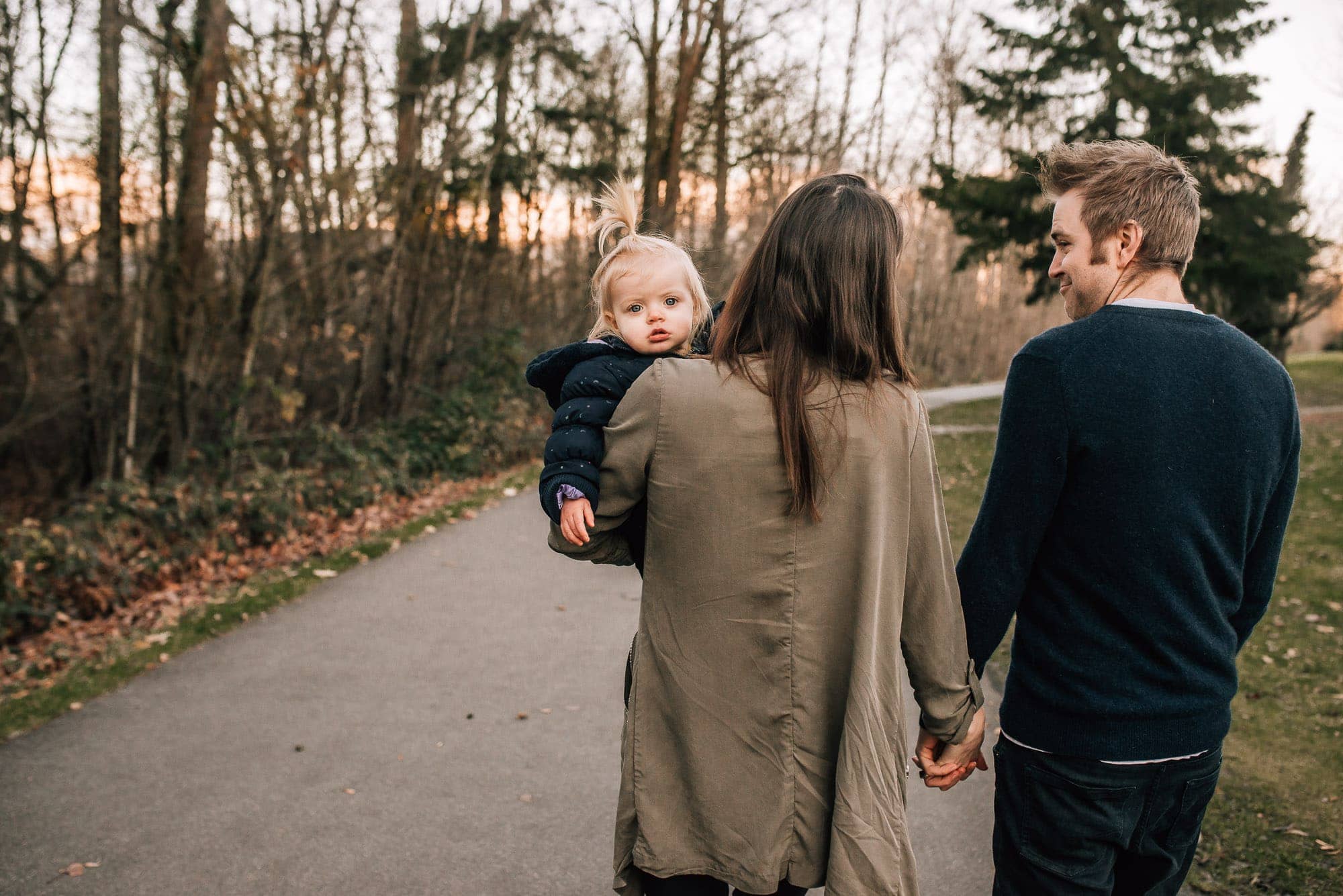 couple walks away from camera while girl looks at Vancouver Family Photographer