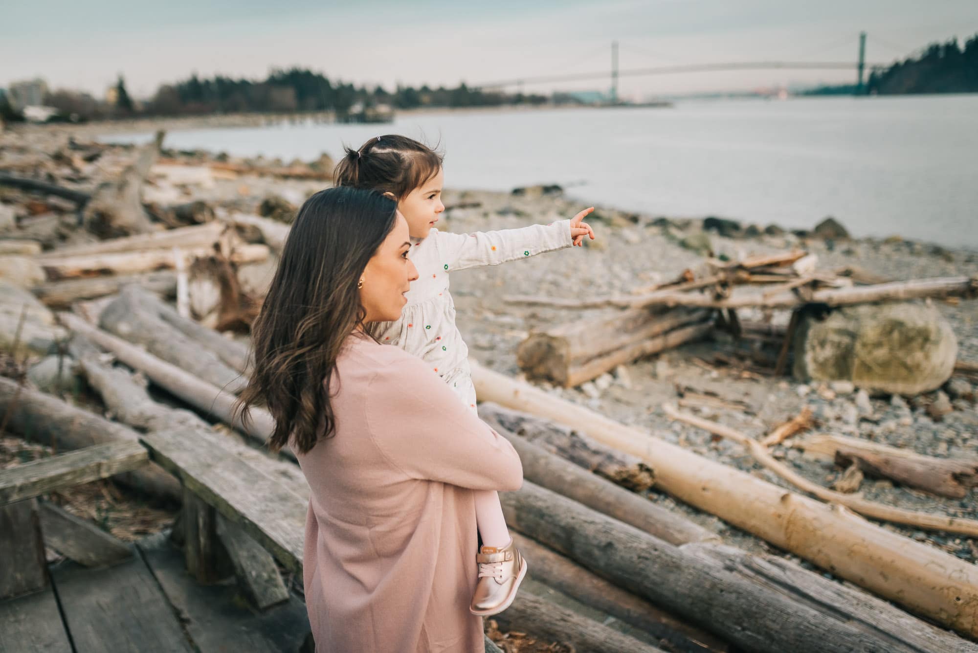 pregnant mom and daughter looking out over beach and Lions Gate bridge during family photos