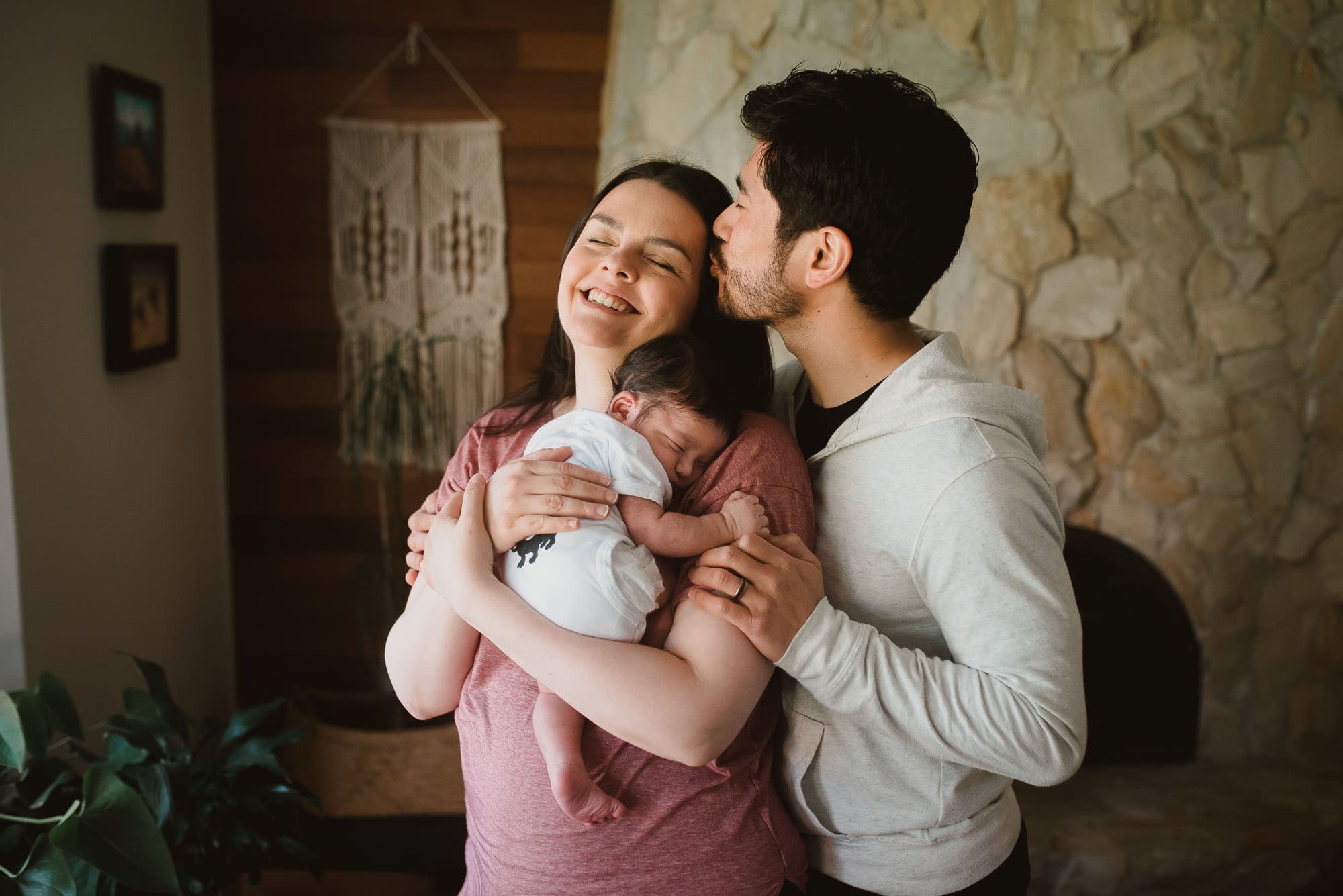 dad kisses mom with newborn baby for newborn photos