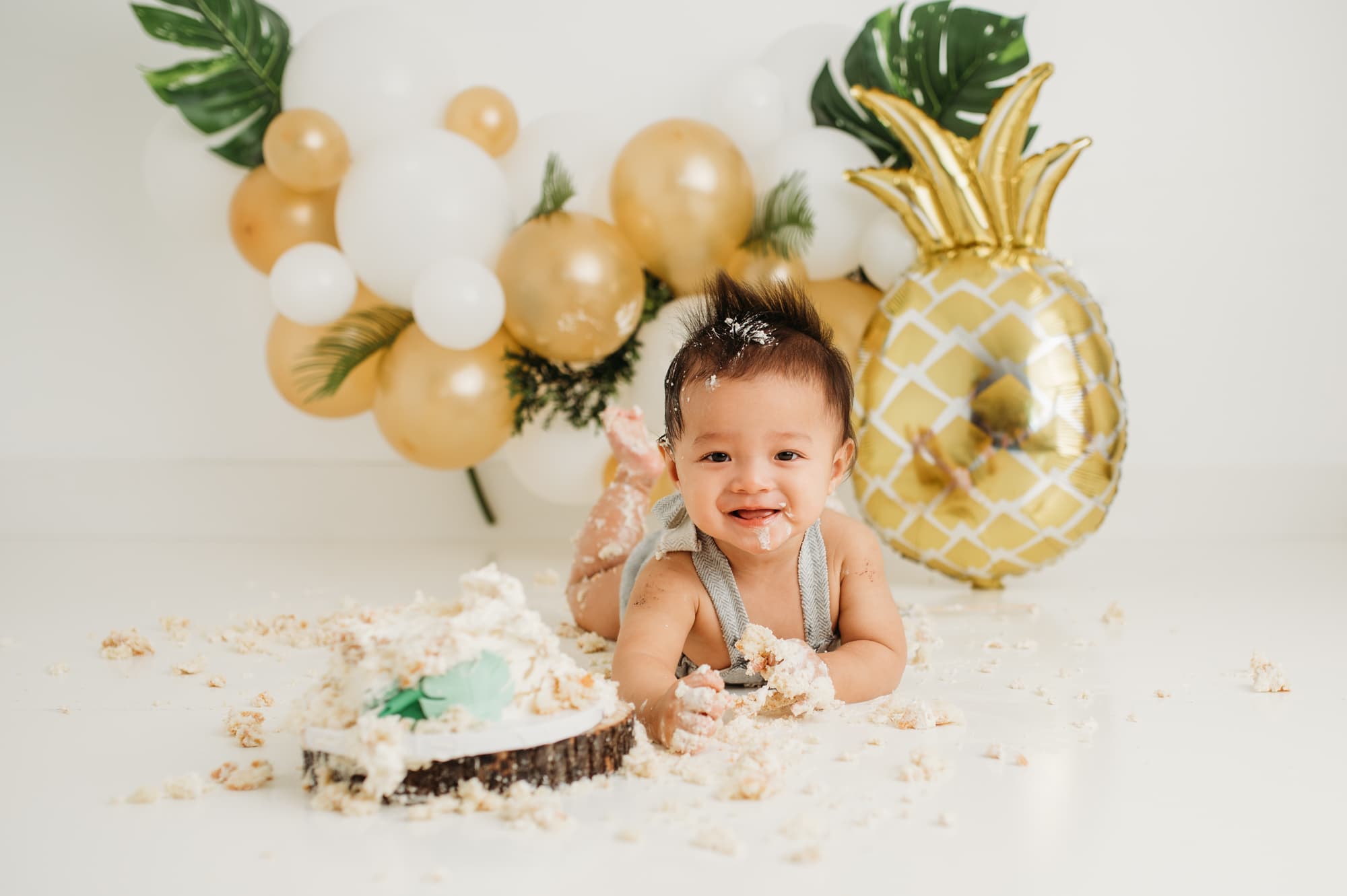 Happy and laughing boy lies next to a cake in a Vancouver cake smash portrait session.