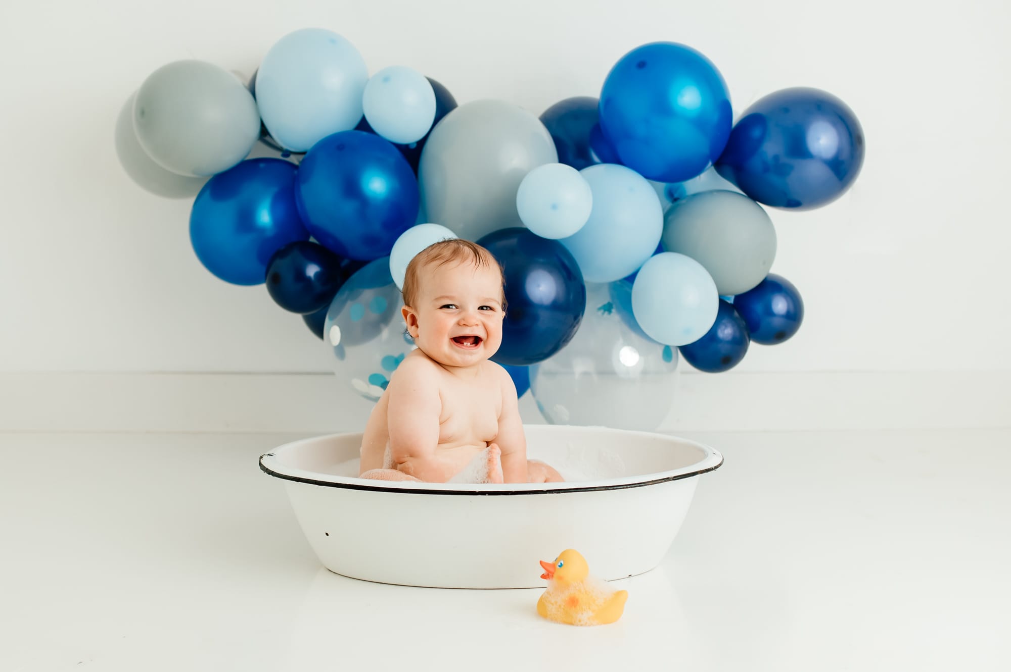Bubble bath session in vintage tub with blue balloon garland.