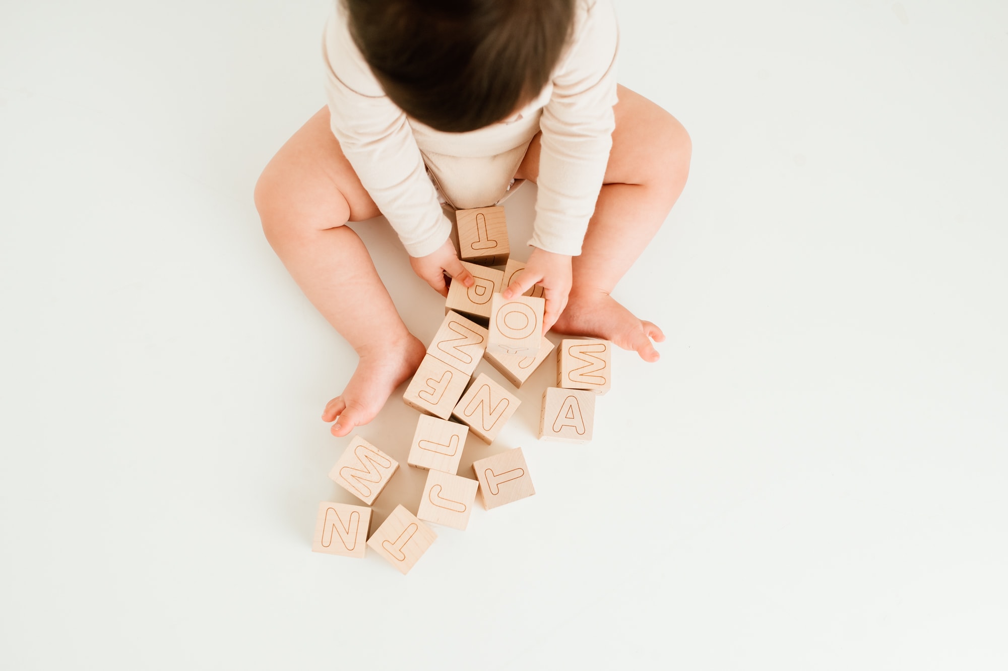 Overhead view of child playing with alphabet blocks in a studio photo session.