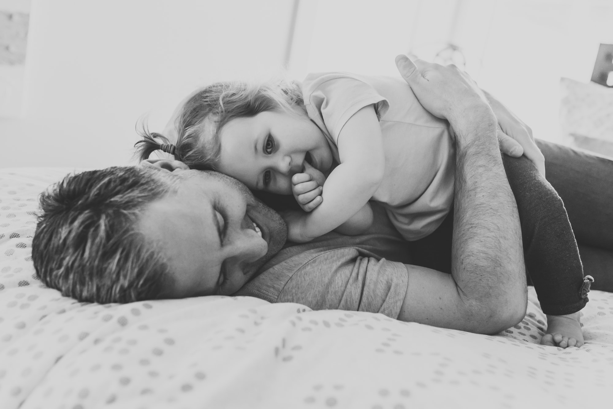 tender family photography moment with girl sucking her thumb while lying on dad's chest
