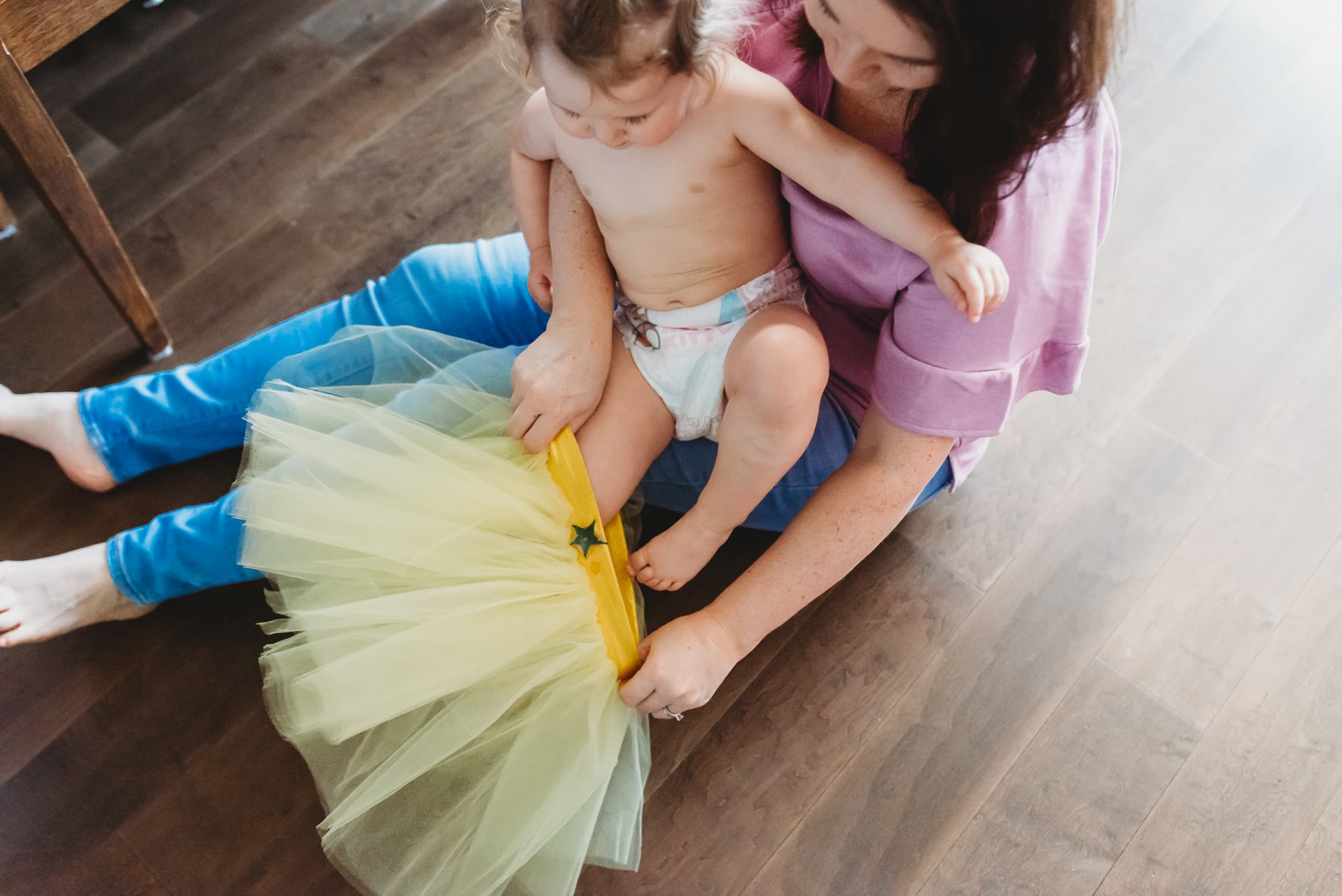 mom helping to put on toddler's yellow tutu