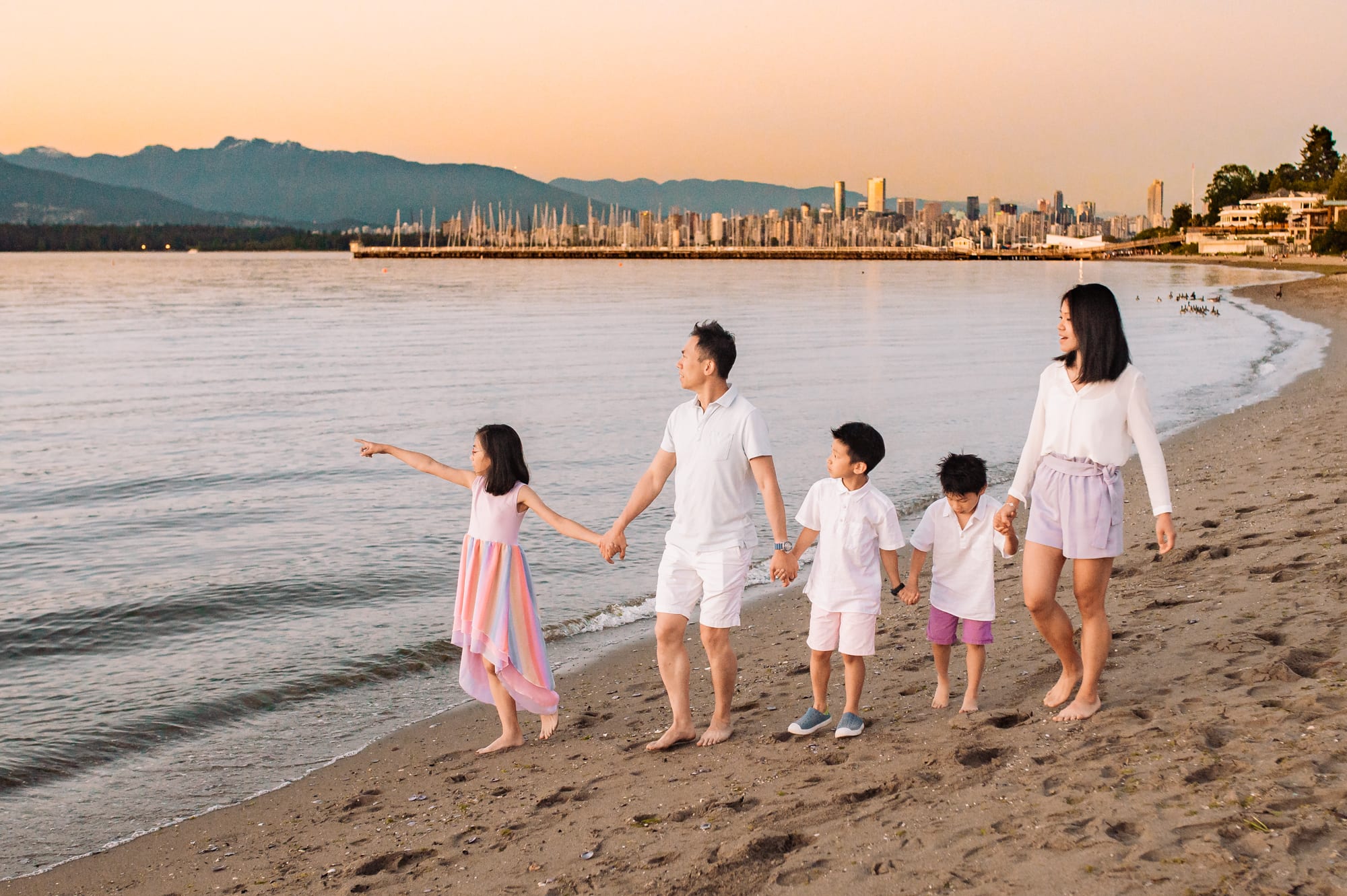 Asian family of 5 walk on the beach in Vancouver westside beach park family photo session.