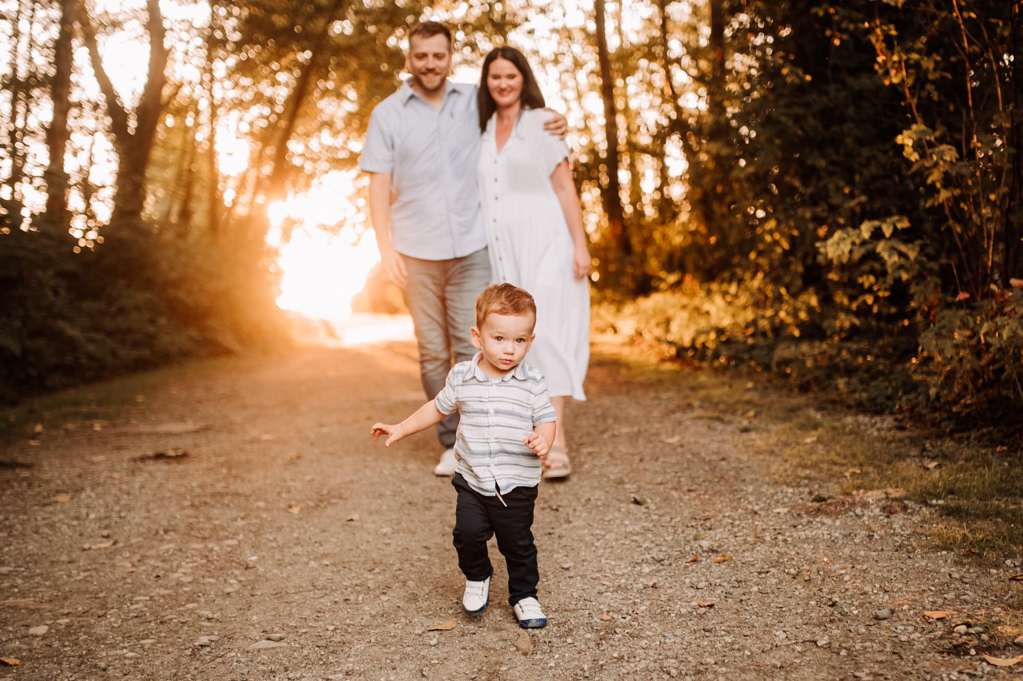 Sunset family photo session in Burnaby shows little boy walking ahead of his parents on road.