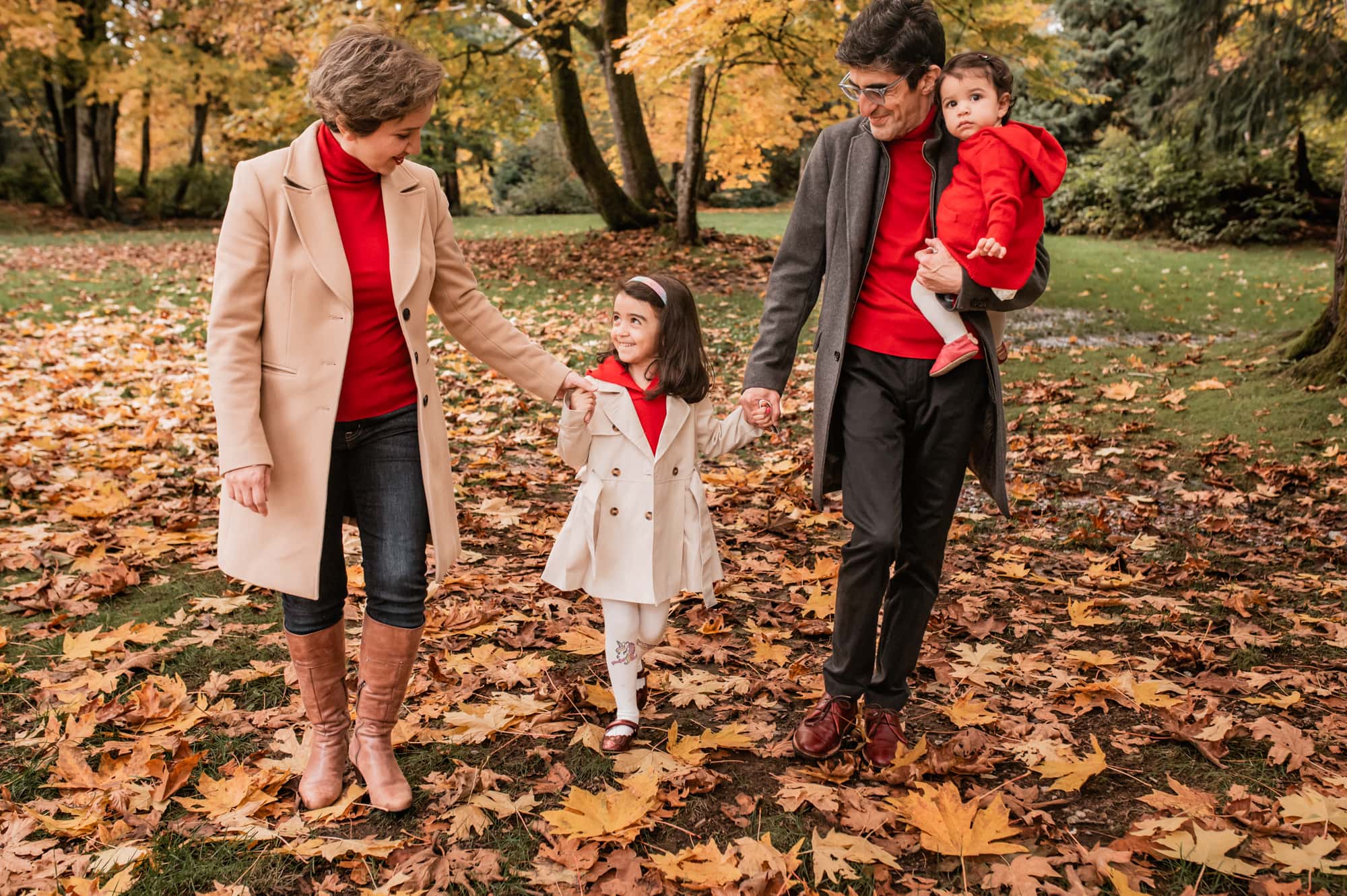 Family of 4 walks through the fall leaves in Cates Park in North Vancouver.