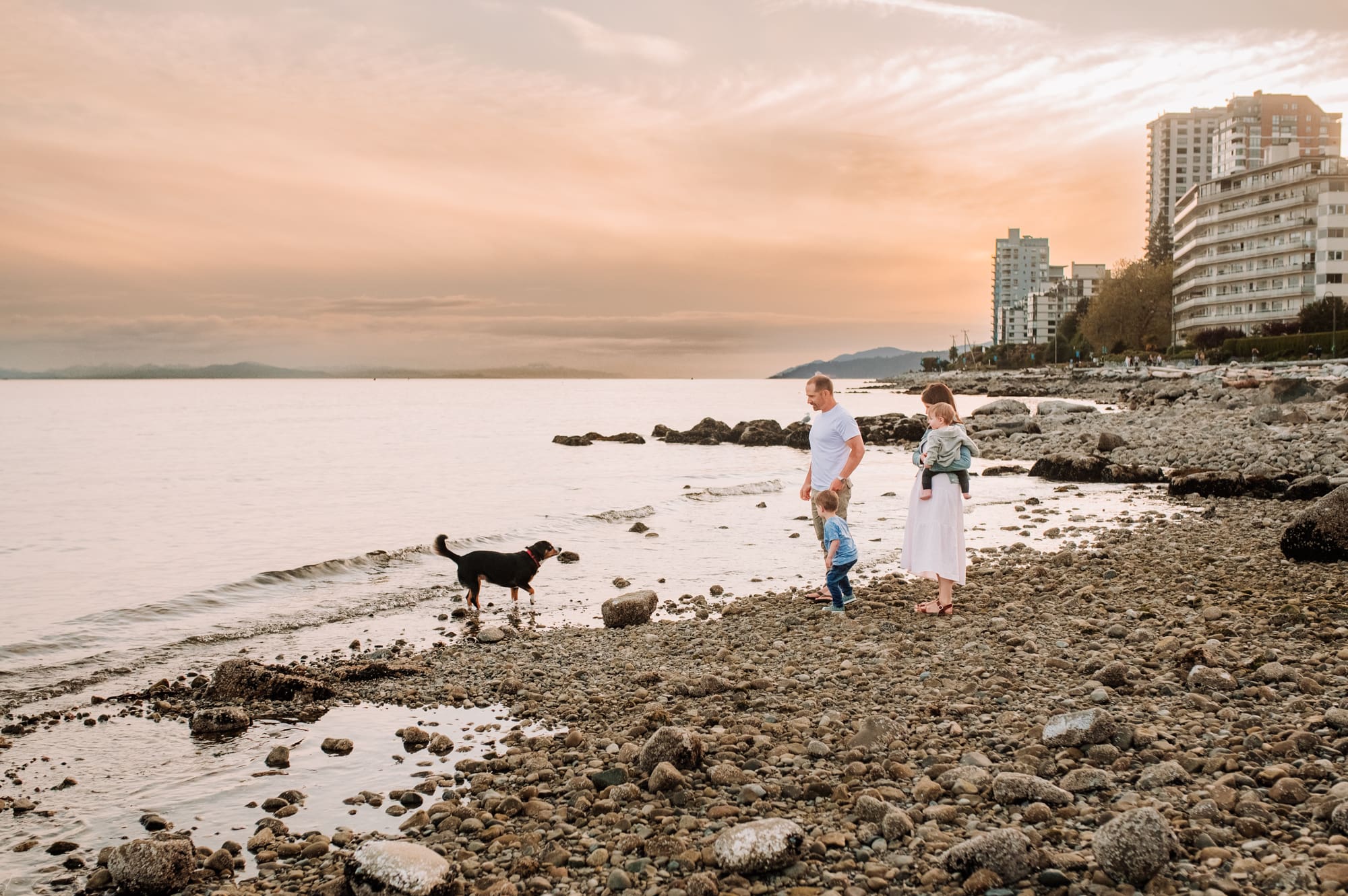 Family walks on the beach at Ambleside in West Vancouver during a family session with their dog.