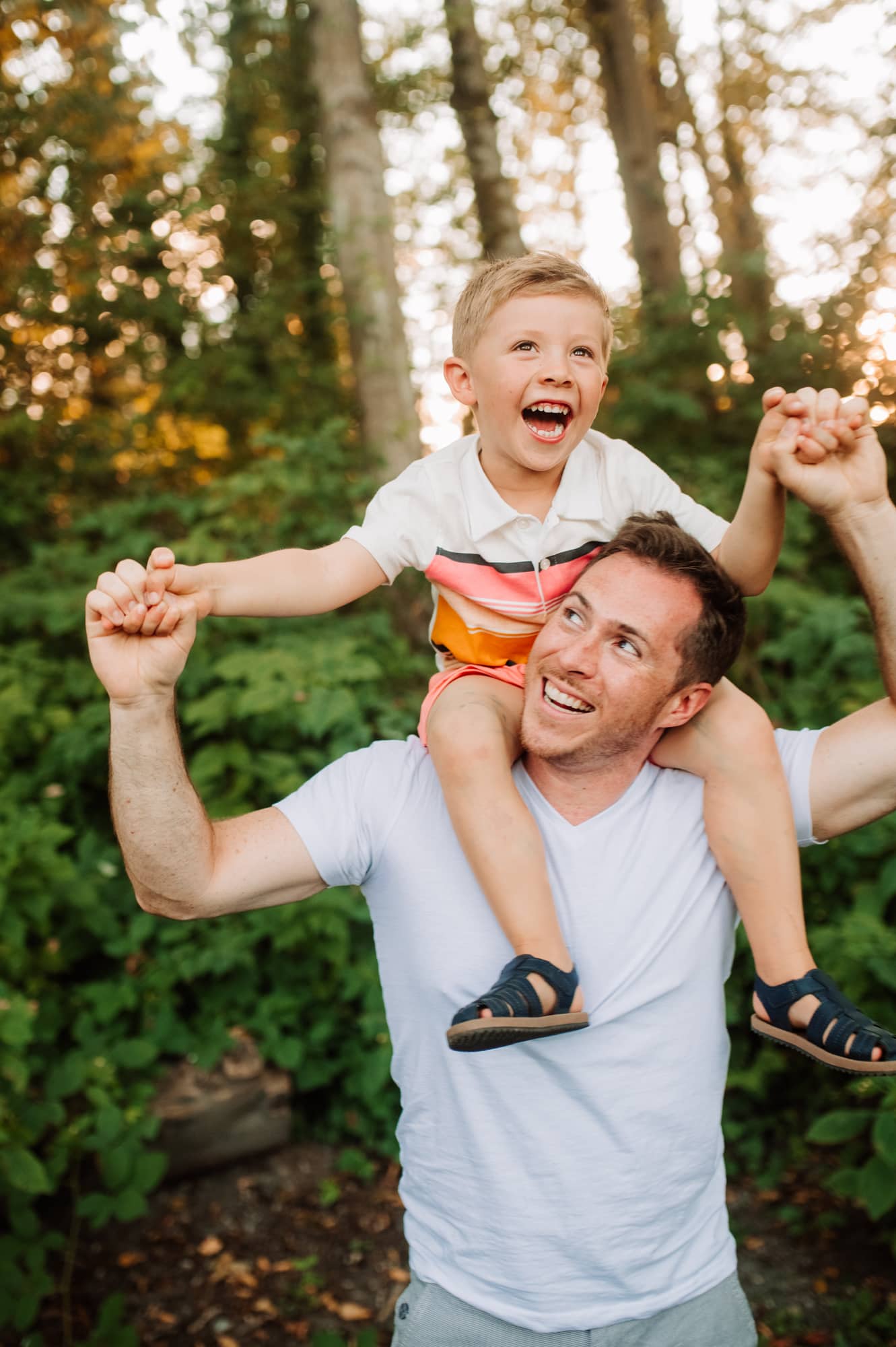 Boy laughs while riding on his dad's shoulders in Burnaby park.