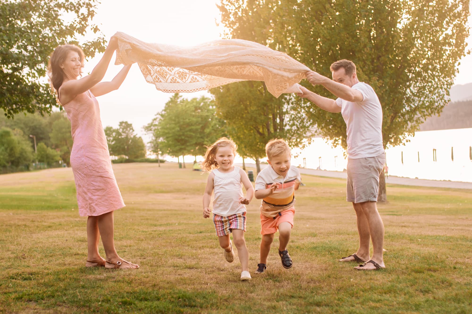 Twin boy and girl excitedly run under a blanket parachute during their Barnet Marine Park photo session.