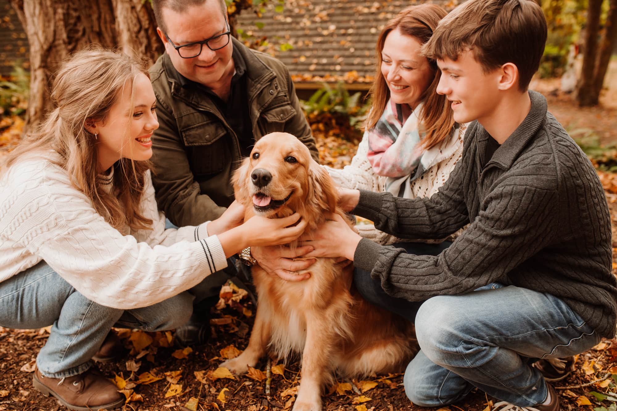 Family huddles around golden Labrador dog in Deer Lake family photo session.