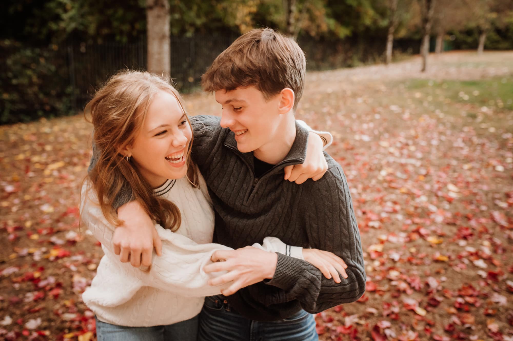 Teenage brother and sister playfully wrestle in Burnaby family photography session.