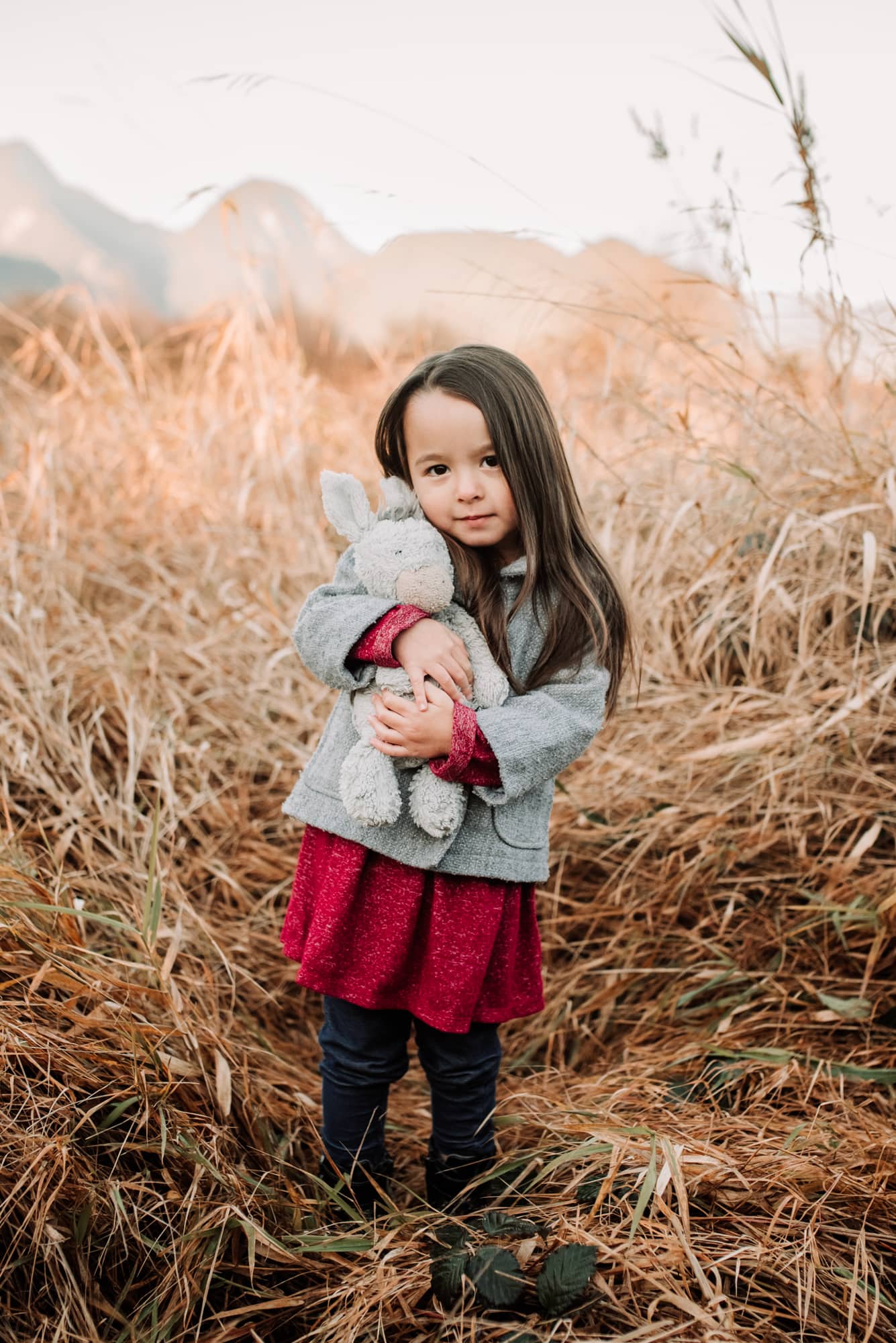 Vancouver Family Photographer shows girl holding teddy bear in reeds during family photo session